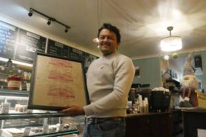 Modern Bakeshop & Cafe owner and business partner Ranjeet Bhojiya, holding a sign with the store&rsquo;s historical bread products, pictured Thursday, Dec. 18. (Evert Lindquist/Revelstoke Review)