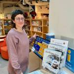 Alison Holm demonstrates the Riverfront Centre&rsquo;s digital kiosk alongside the official Games guide available for visitors.